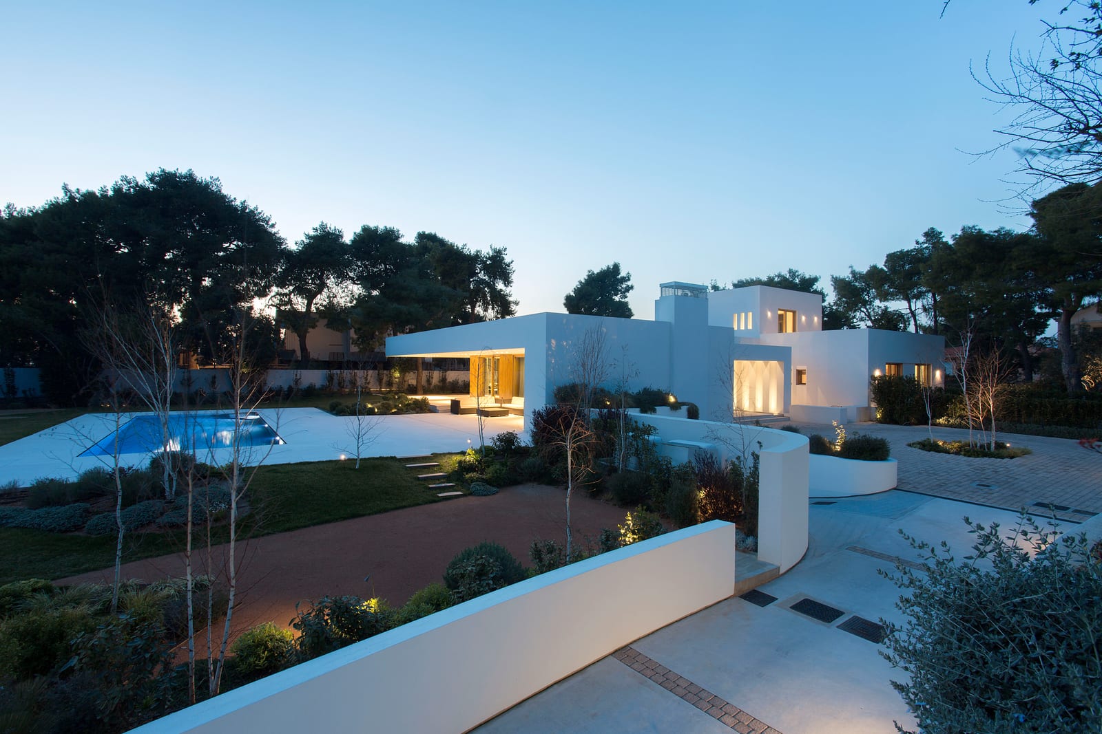 Il·luminació exterior Linea Light en una vila blanca amb piscina i pins