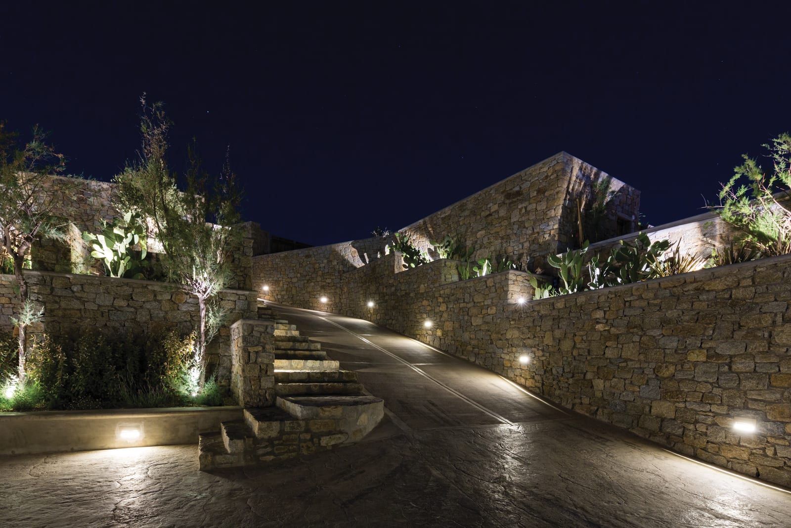 Il·luminació d'esglaons i murs Linea Light al llarg d'un camí de jardí amb murs de pedra a Míkonos
