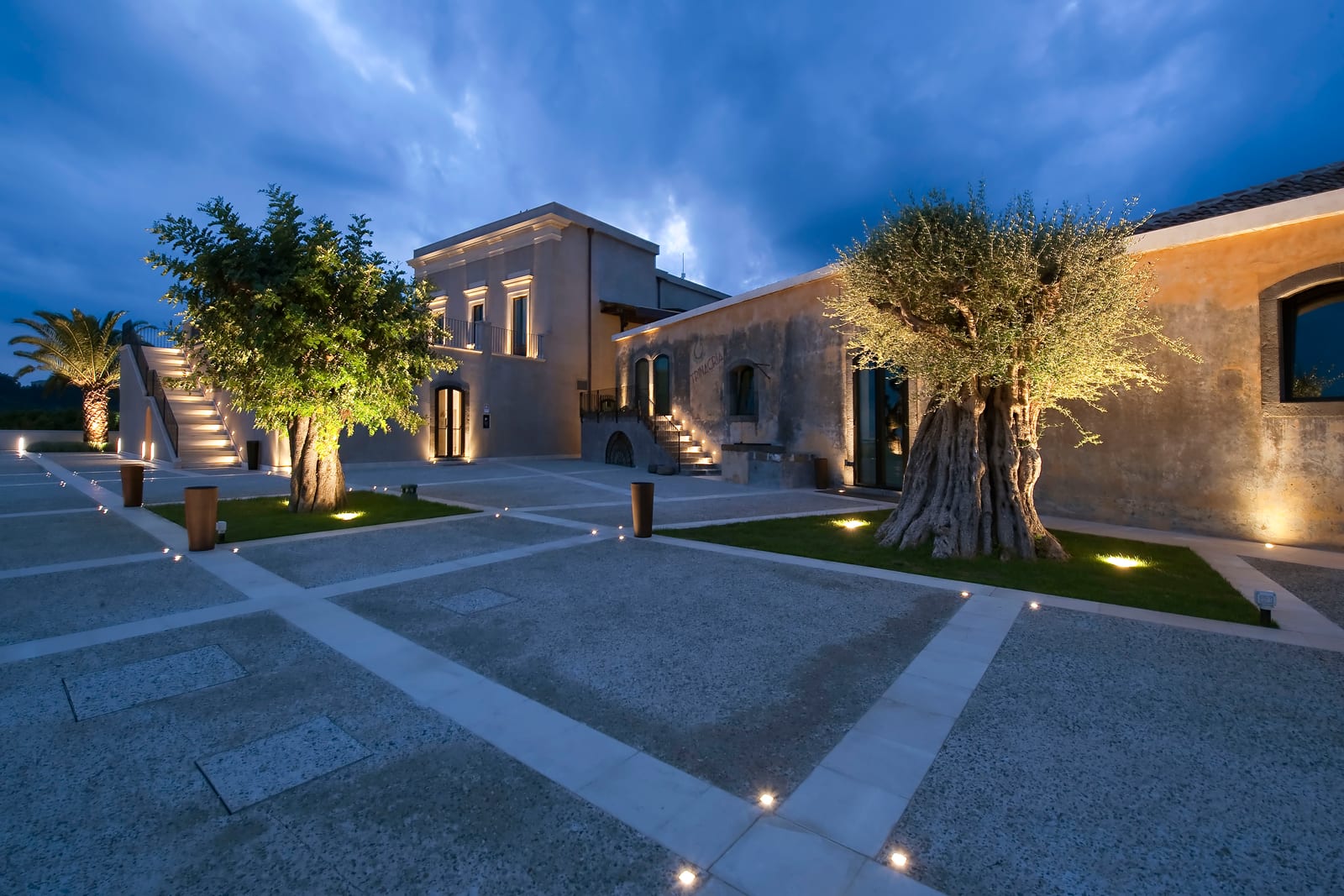 Encastats de terra Linea Light il·luminant oliveres en un pati de pedra sicilià