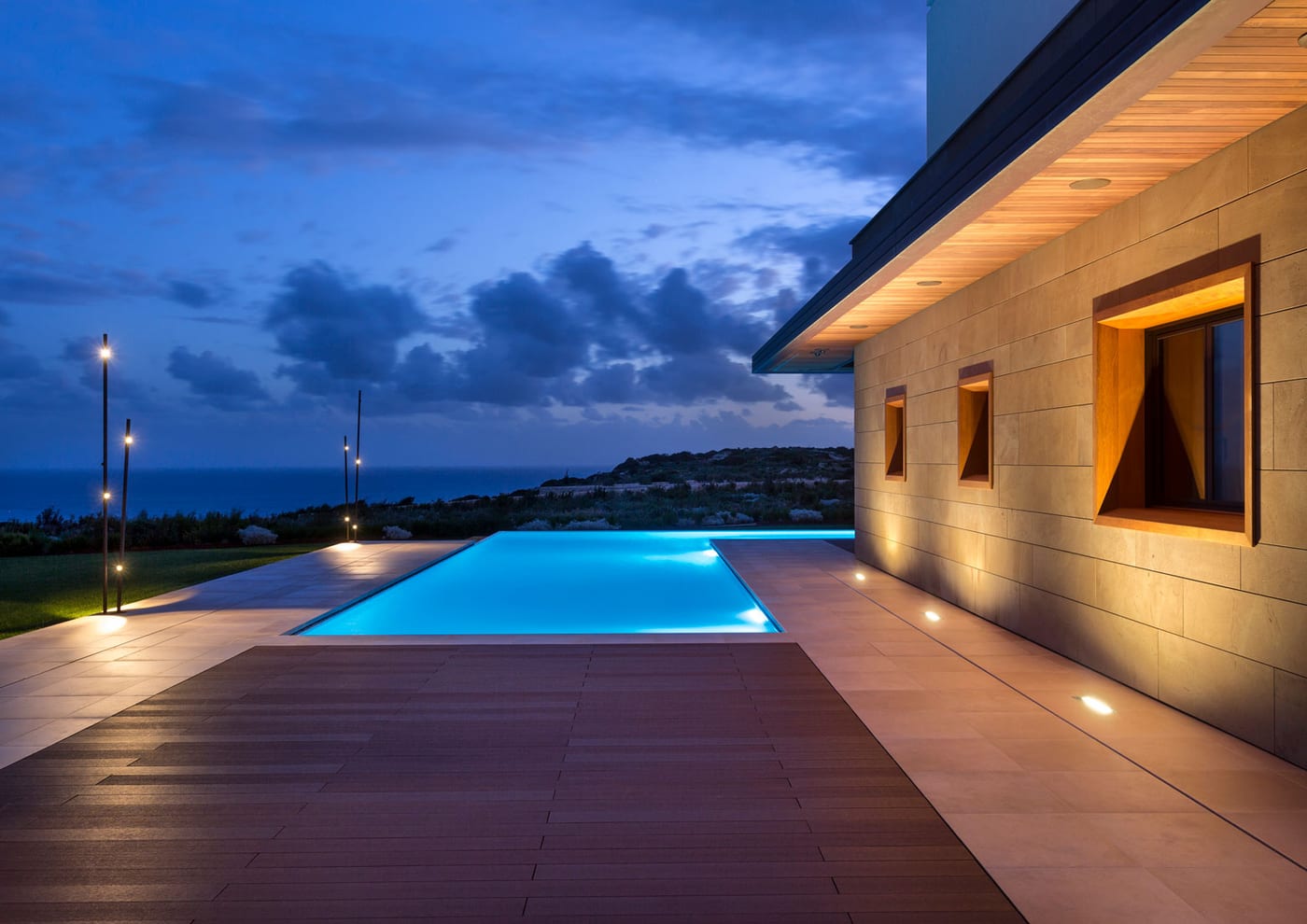 Llums d'exterior Vibia Bamboo al costat d'una piscina desbordant amb vistes a la mar