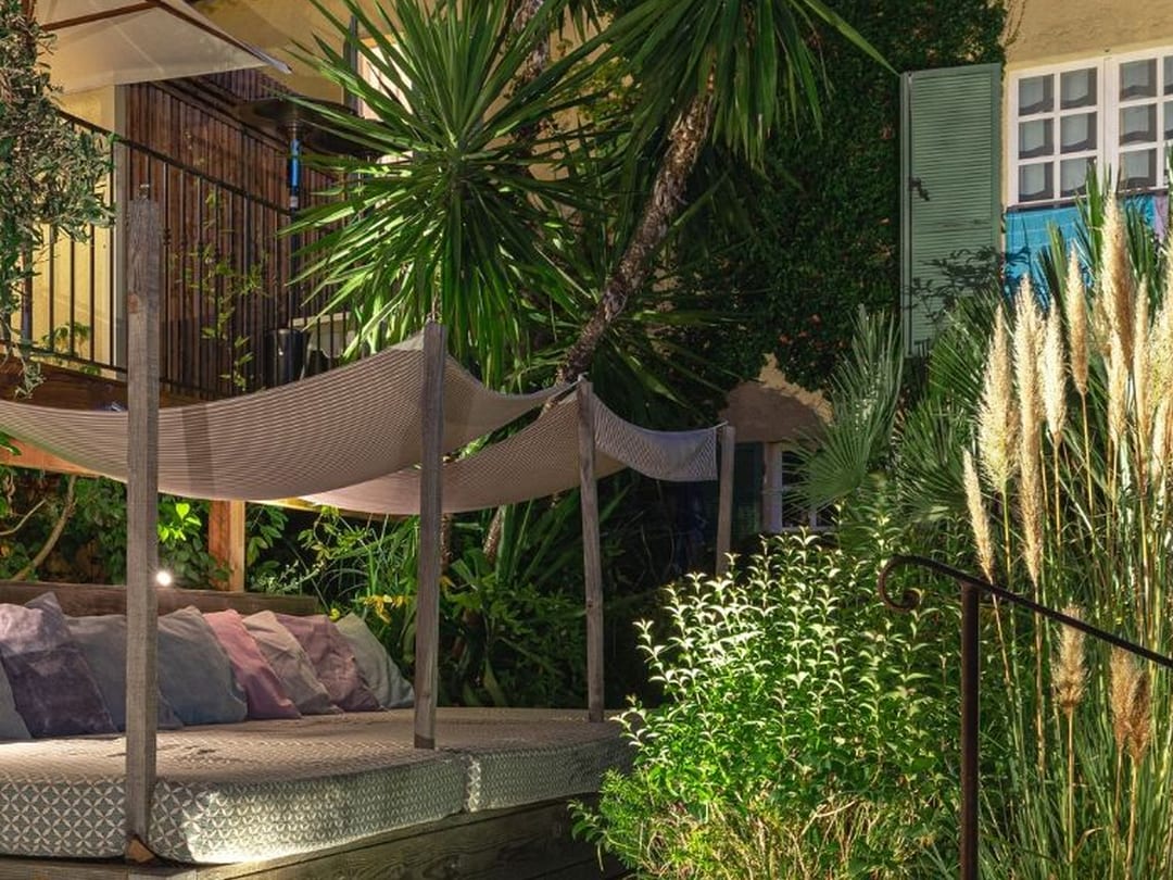 Courtyard with palm and shade sail lit at dusk