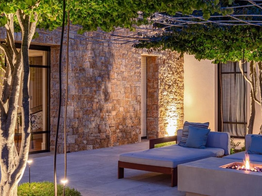 Terraza con pérgola, brasero y luces de jardín en una finca de piedra