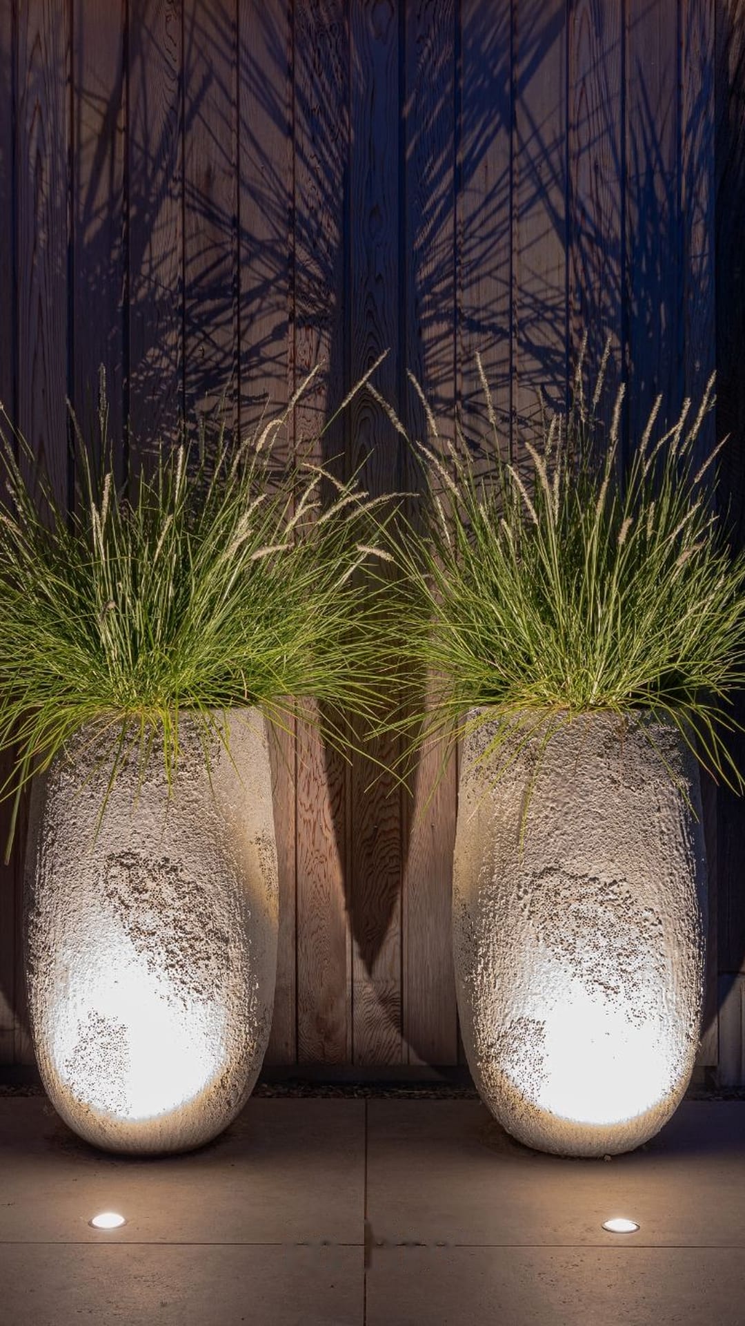 Large stone planters uplit by in-ground lights